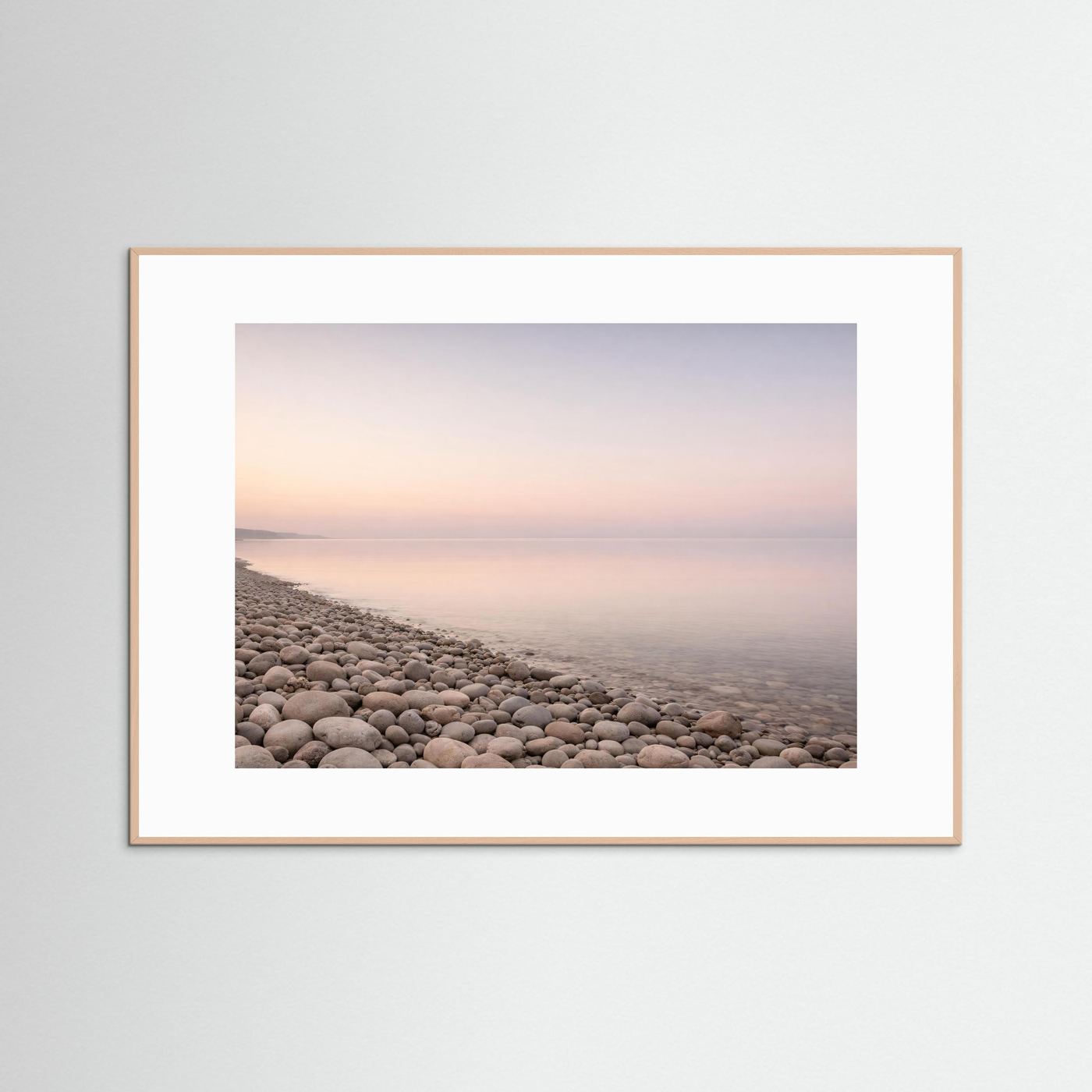 Querformat-Poster im hellen Holzrahmen mit Kiesstrand und weichem Pastellhorizont