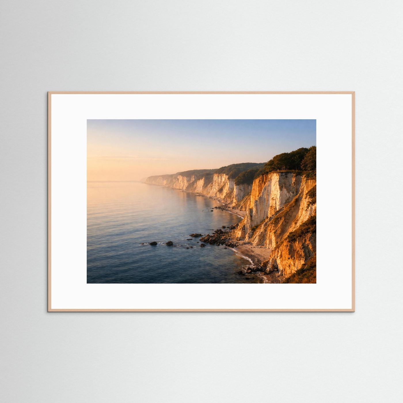 Wandbild mit hellem Holzrahmen: Steilküste und Meer bei Sonnenaufgang