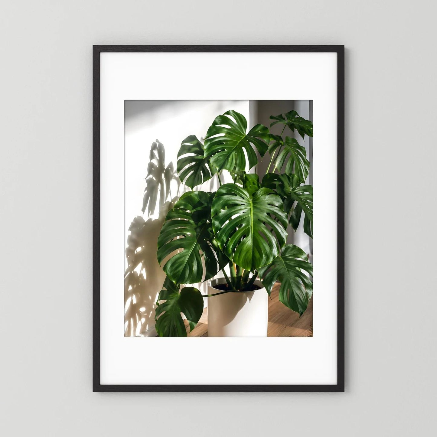 Monstera-Poster mit schwarzem Rahmen, grüne Blätter im weißen Pflanztopf