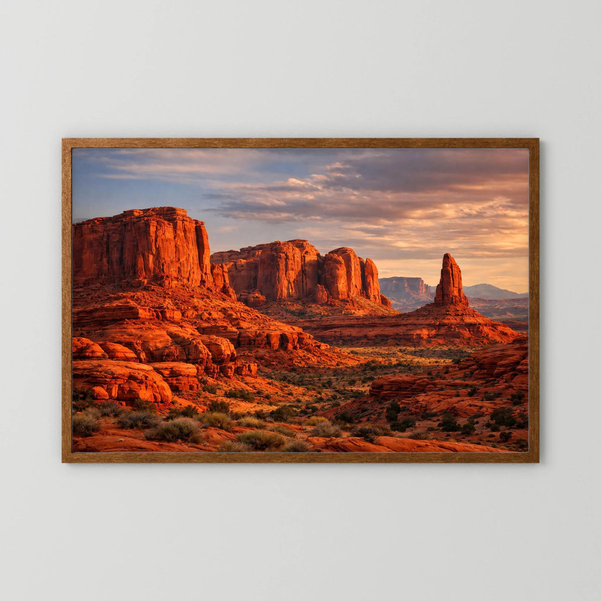 Gerahmtes Wandbild mit roter Felslandschaft im Abendhimmel, brauner Holzrahmen, Querformat.