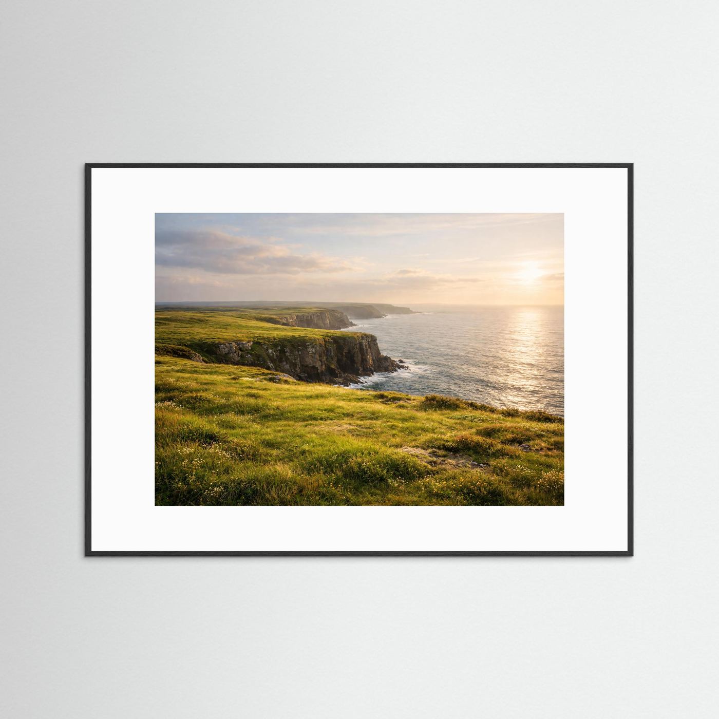 Querformat-Poster: grüne Klippen am Meer bei Sonnenuntergang, schwarzer Rahmen mit weißem Rand