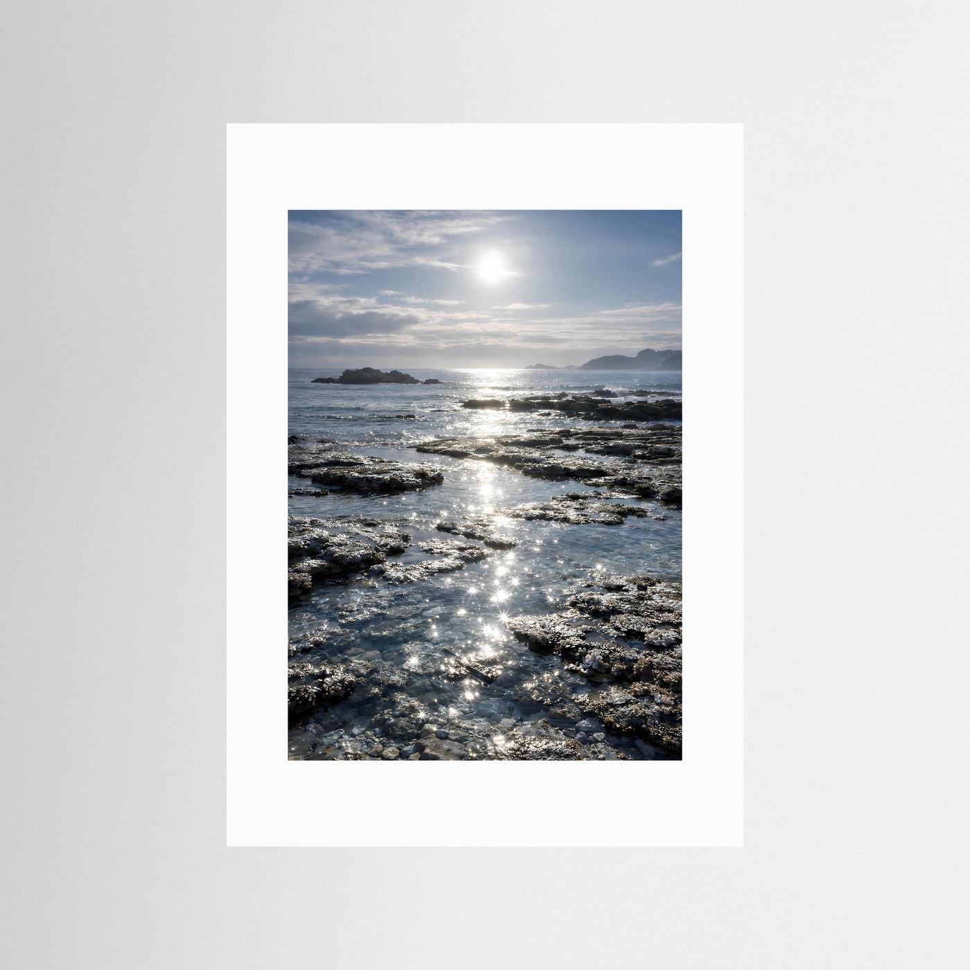 Küstenposter im Hochformat mit weißem Passepartout, Felsen und Sonnenreflexen