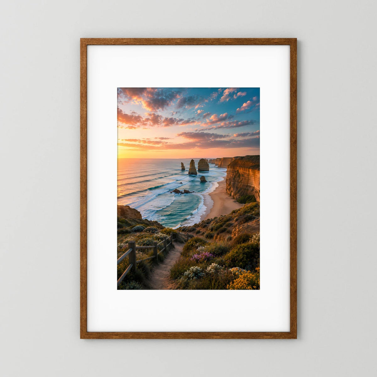Hochformat-Poster im braunen Holzrahmen: Küste bei Sonnenuntergang mit Felsnadeln und Strandweg.