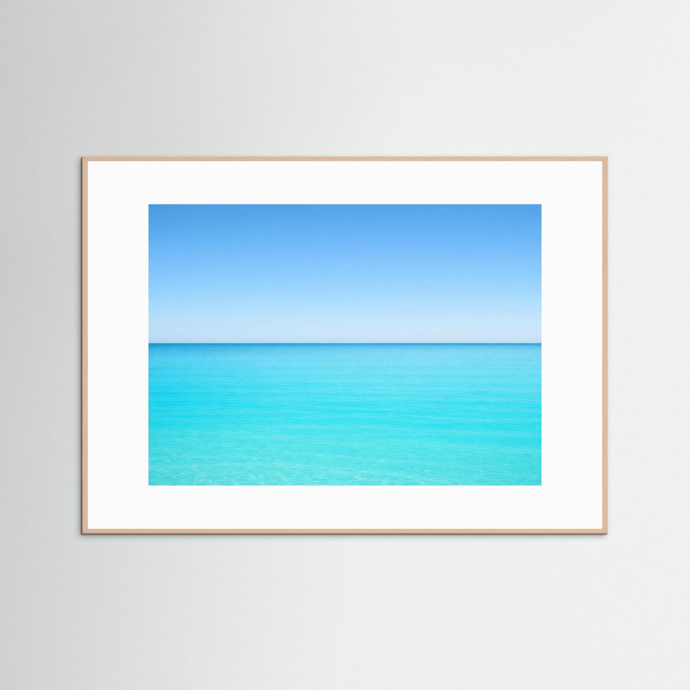Meerposter im Querformat mit hellem Holzrahmen und weißem Passepartout, türkis-blauer Horizont