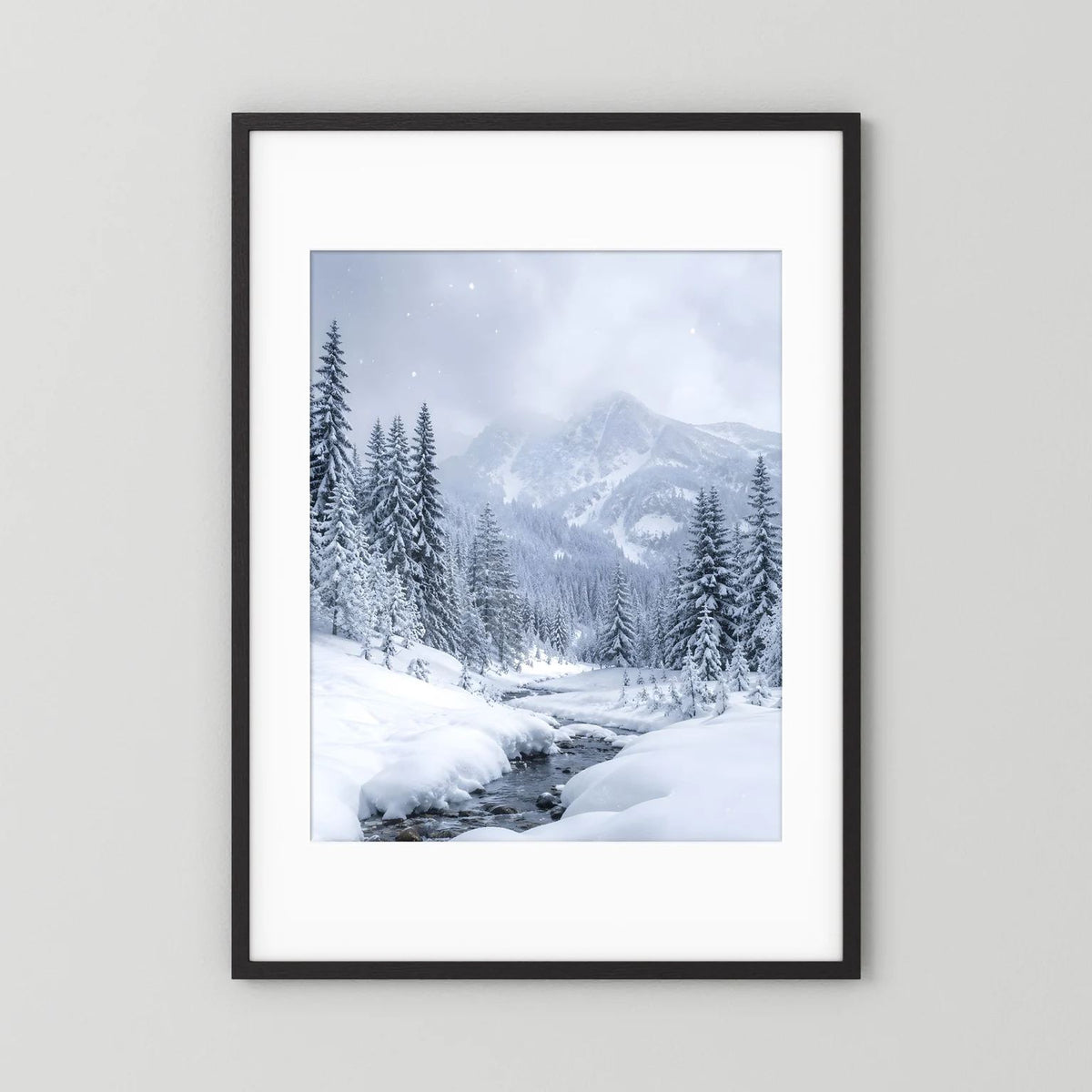 Winterlandschaft-Wandbild mit schwarzem Rahmen und weißem Passepartout: verschneite Berge und Tannen.