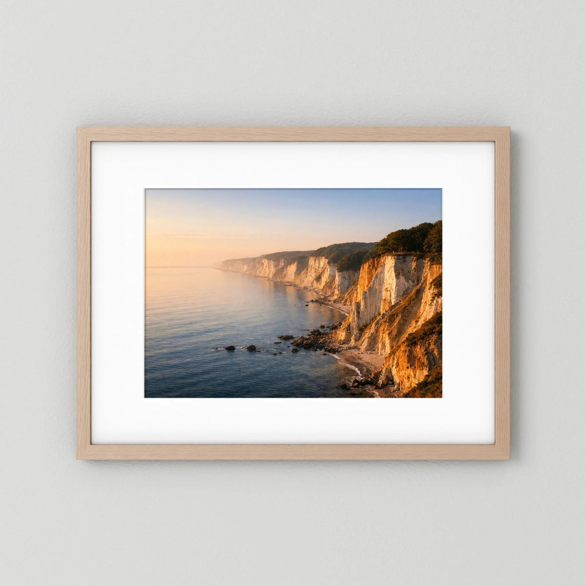 Querformatiges Wandbild mit hellem Holzrahmen: Ostsee-Klippen bei Sonnenaufgang