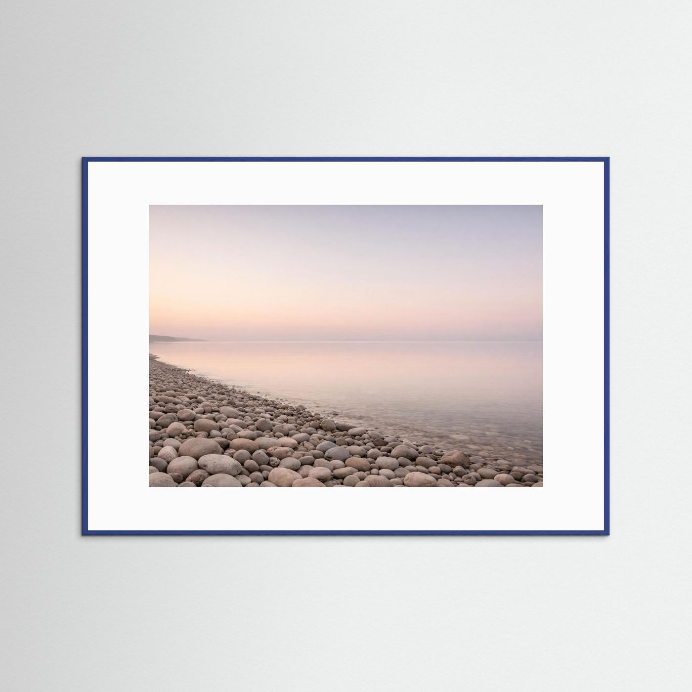 Querformat-Poster im blauen Rahmen mit Kiesstrand und ruhigem Meer im Pastelllicht