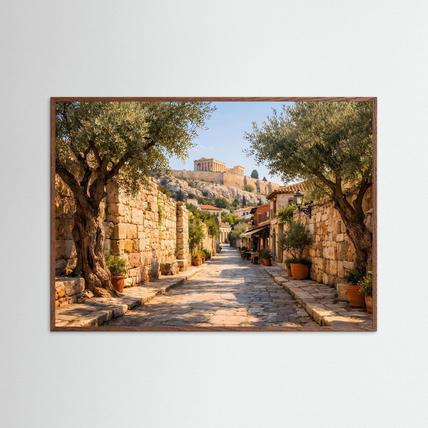 Wandbild mit mediterraner Gasse, Olivenbäume und Steinstraße, brauner Holzrahmen.