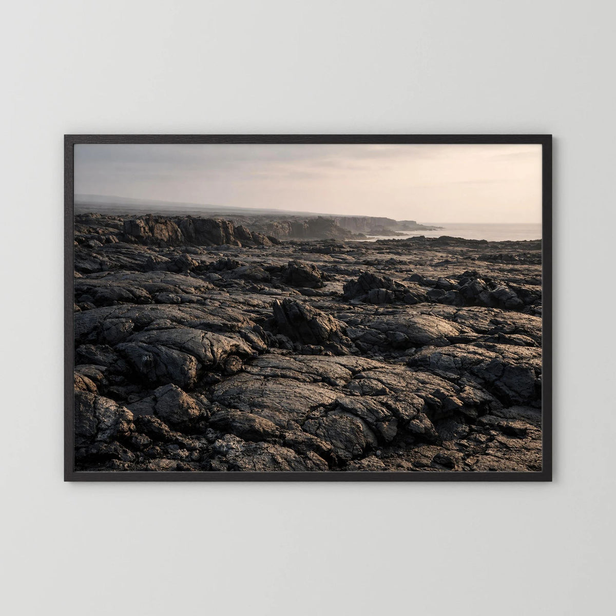 Querformat-Wandposter mit Lavafelsen an der Küste im schwarzen Holzrahmen