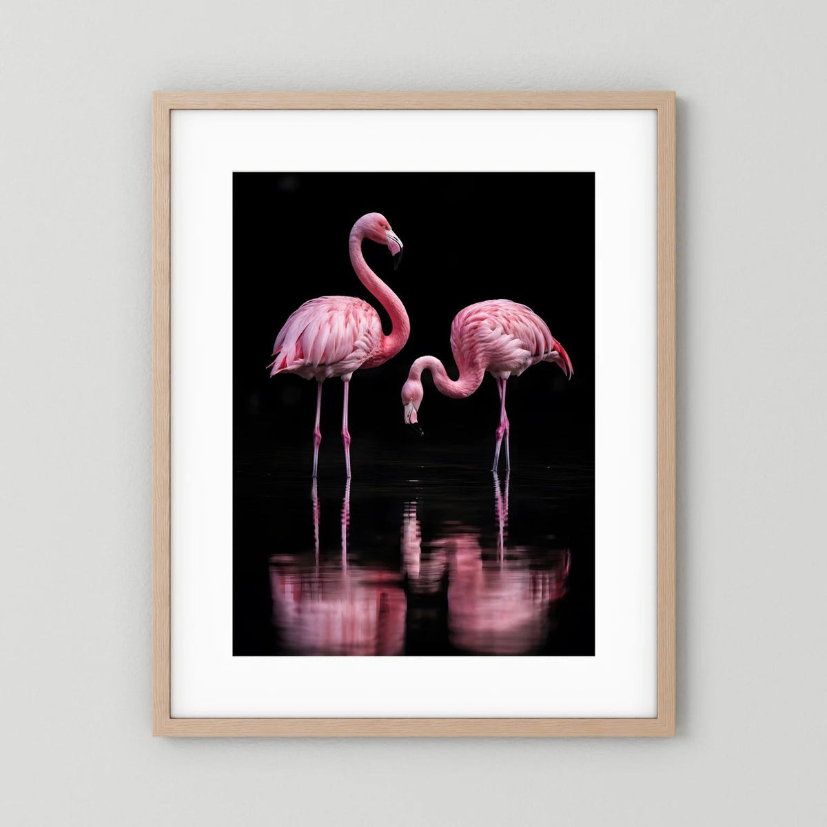 Hochformatiges Poster mit zwei rosa Flamingos in hellem Holzrahmen; schwarzer Grund mit Spiegelung