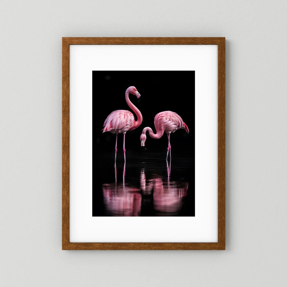 Hochformatiges Poster mit zwei rosa Flamingos in braunem Holzrahmen; schwarze Fläche mit Spiegelung