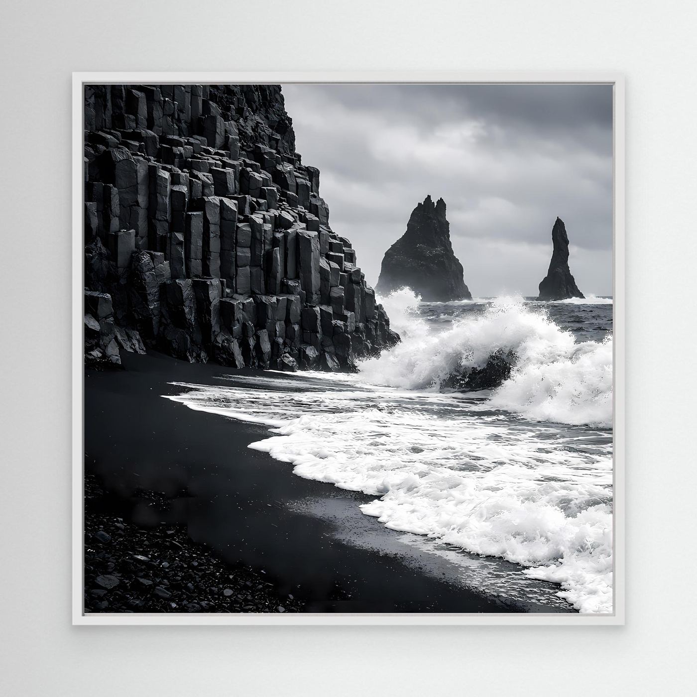 Leinwandbild mit weißem Rahmen: schwarzer Sandstrand, Basaltsäulen und Gischt, Schwarzweiß