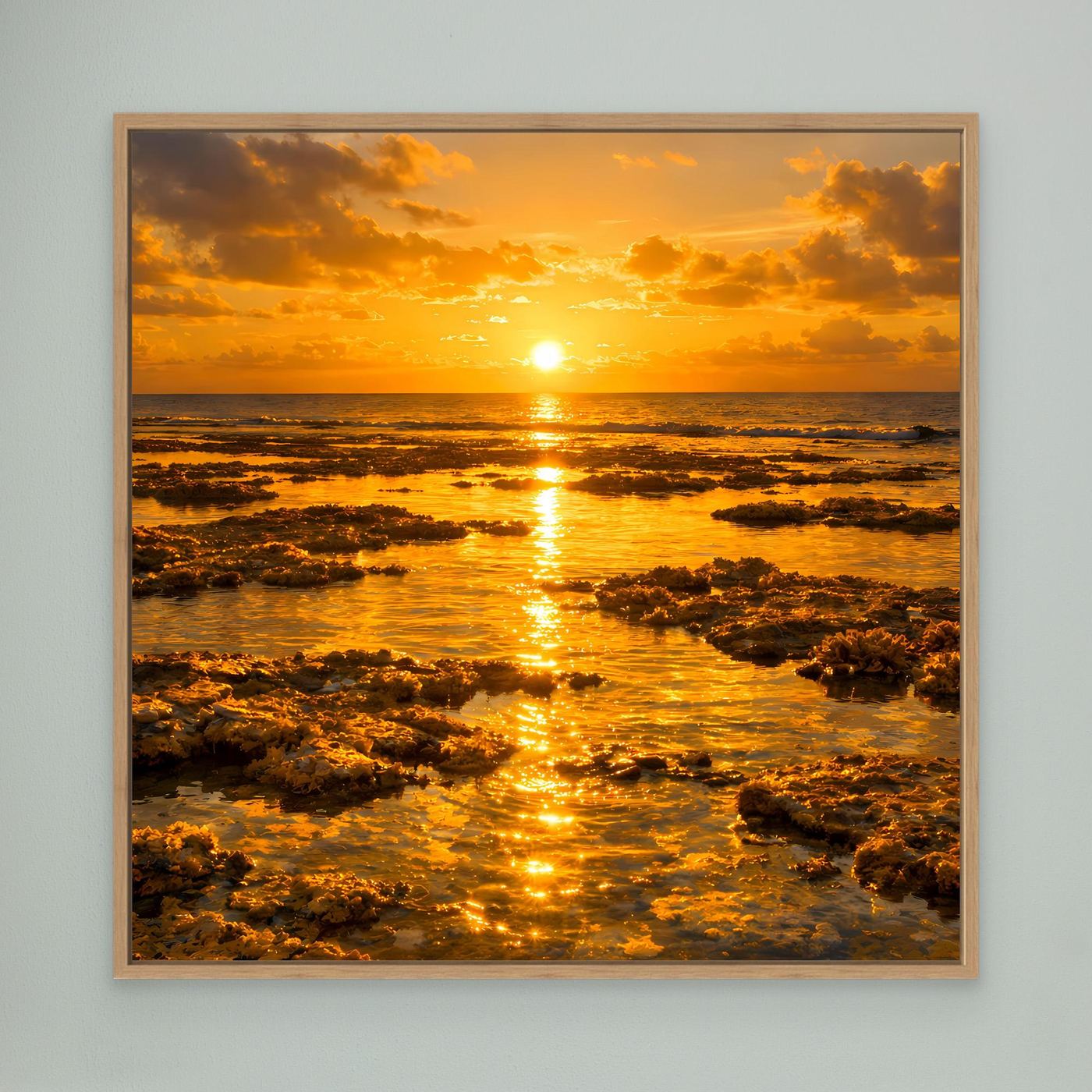 Leinwandbild mit hellem Holzrahmen: goldene Sonne am Meer mit Felsen im Vordergrund.