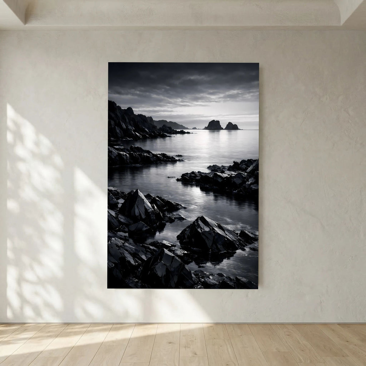 Hochformatiges schwarzweißes Wandbild zeigt Küste mit Felsen und sanftem Wasserverlauf