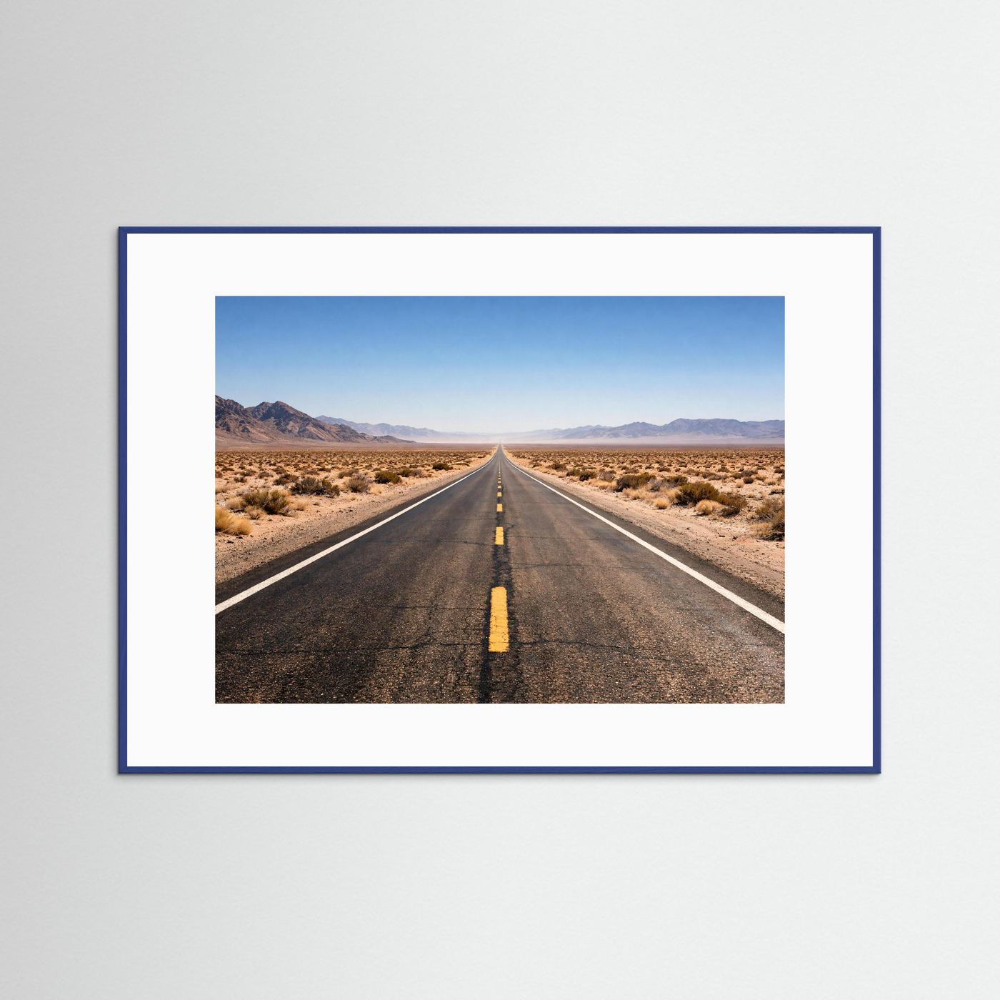Wandbild mit Foto einer langen Straße durch die Wüste, im blauen Rahmen