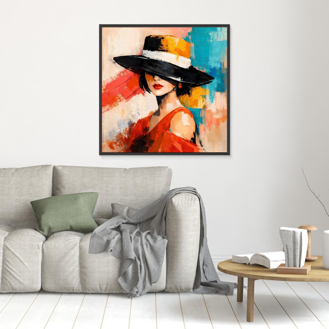 Black-framed wall art of a woman in a black hat and red dress above a gray sofa