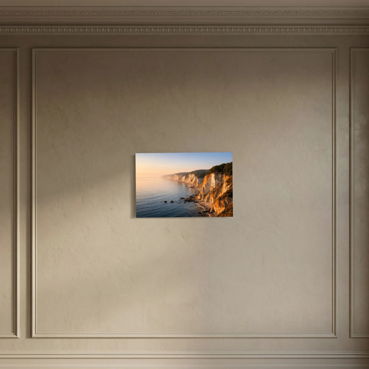 Wandbild mit Küstenfelsen und Meer bei Sonnenaufgang, mittig vor der Wand