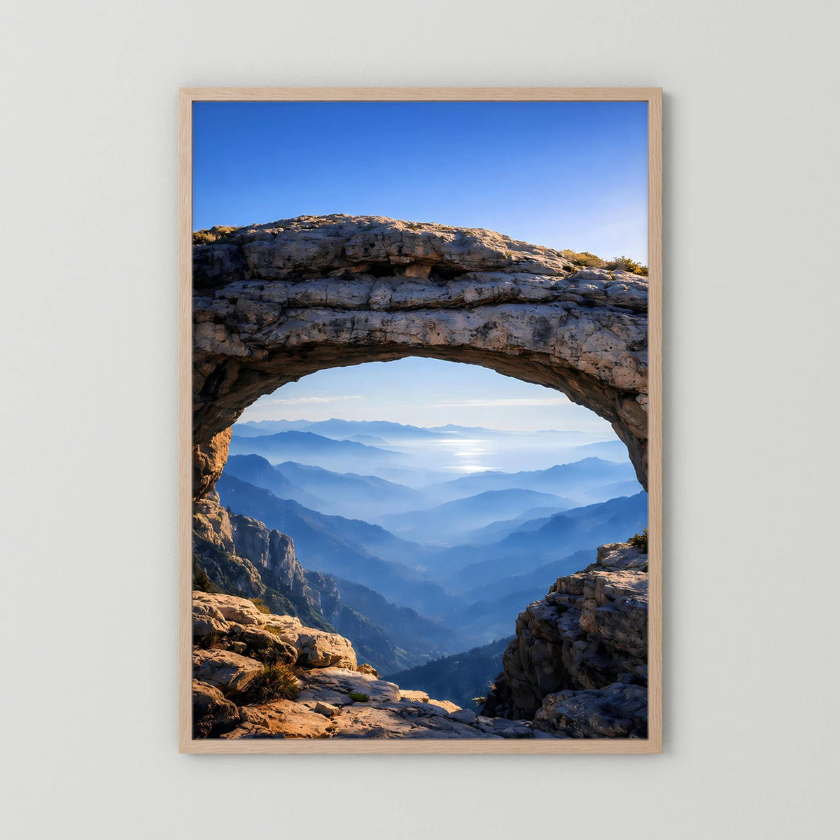 Hochformatiges Poster im hellen Holzrahmen mit Felsbogen und Bergpanorama