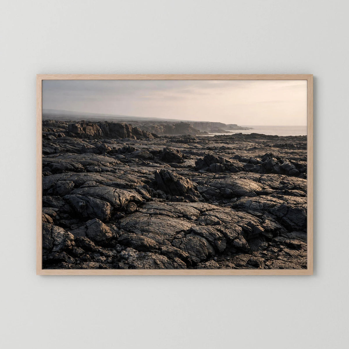 Querformat-Wandposter mit Lavafelsen an der Küste im hellen Holzrahmen